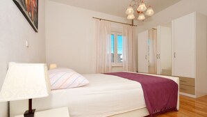 A bedroom with a bed, a bedside lamp, a window with curtains, a mirror, and a wardrobe. - Zita - Spacious Apt with 2 Bedrooms & 2 Bathrooms, Kaštel Novi (Kaštel Novi)