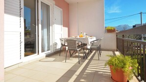 A balcony with a table set for breakfast, chairs, and a potted plant. - Zita - Spacious Apt with 2 Bedrooms & 2 Bathrooms, Kaštel Novi (Kaštel Novi)