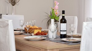 A dining table set with plates, cutlery, glasses, a bottle of wine, and a vase with flowers. - Zita - Spacious Apt with 2 Bedrooms & 2 Bathrooms, Kaštel Novi (Kaštel Novi)