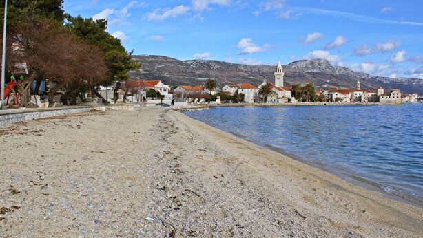 A pebble beach with buildings and a church in the background. - Zita - Spacious Apt with 2 Bedrooms & 2 Bathrooms, Kaštel Novi (Kaštel Novi)