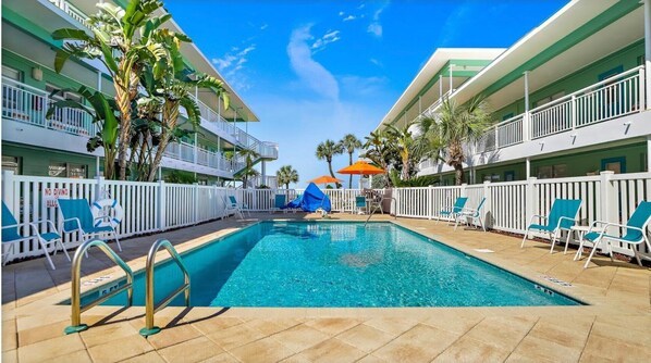 A pool area with clear blue water, white railings, and lounge chairs.