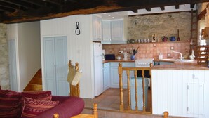 A cozy kitchen with a central island, wooden chairs, and a stone wall.