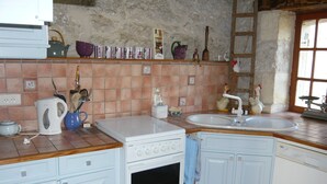A kitchen with white cabinets, a stove, a sink, and a wooden countertop.