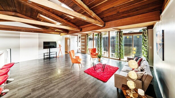 Un vaste espace de vie doté d’un haut plafond en bois, de grandes fenêtres et d’un mobilier moderne.