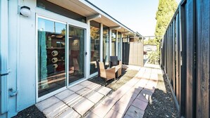 Une maison moderne dotée d’un patio aménagé avec un espace salon et une porte vitrée donnant sur l’intérieur.
