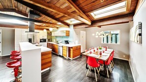 Une cuisine moderne avec des poutres en bois, un îlot central et des tabourets de bar rouges.