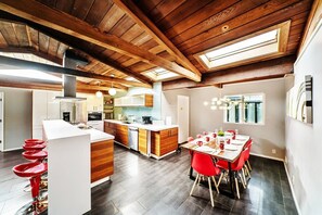 Enjoy meals in this spacious kitchen and dining area, featuring a large table for six and a stylish chandelier.