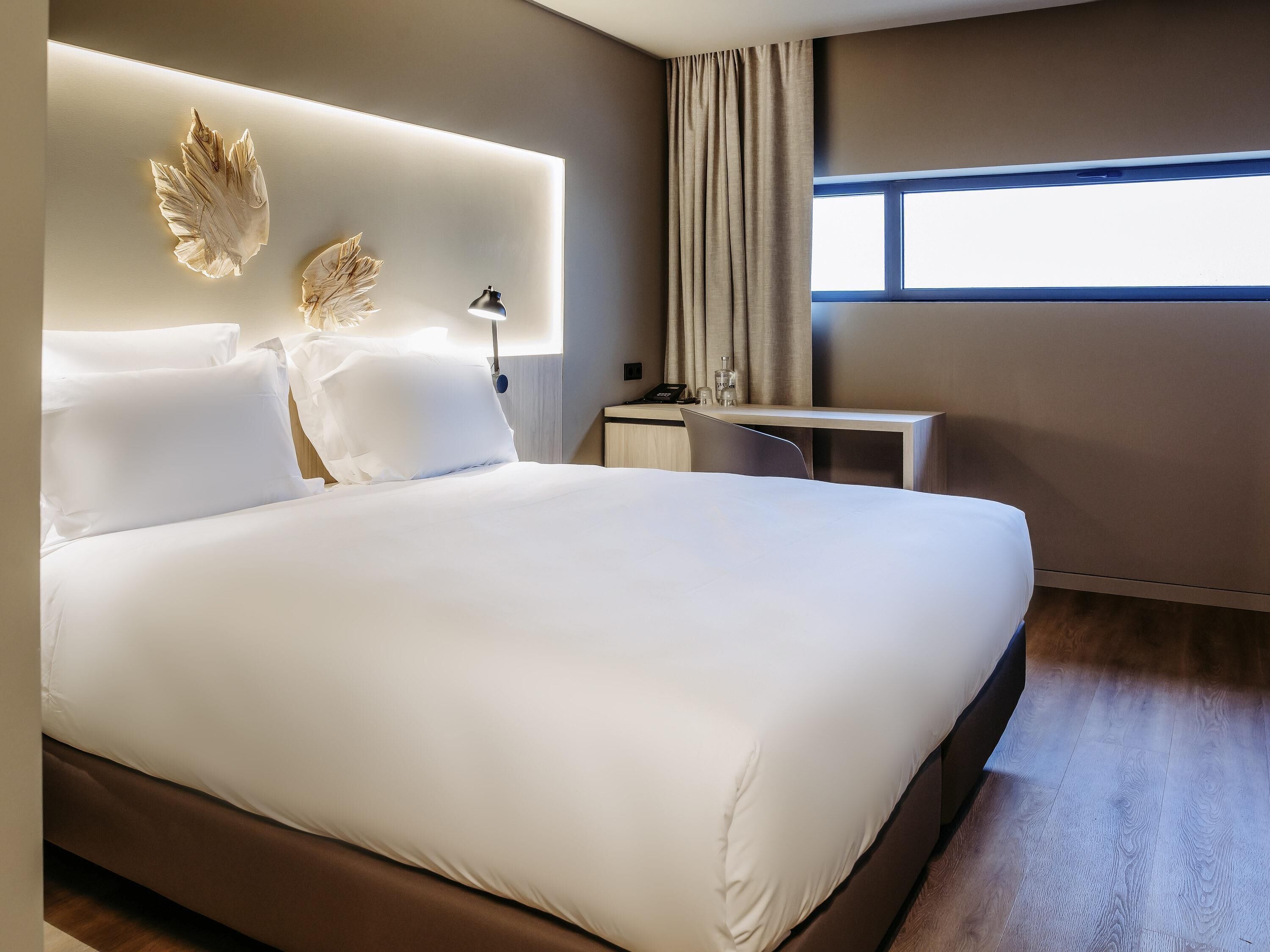 Una habitación de hotel con una cama grande, un escritorio y una ventana.