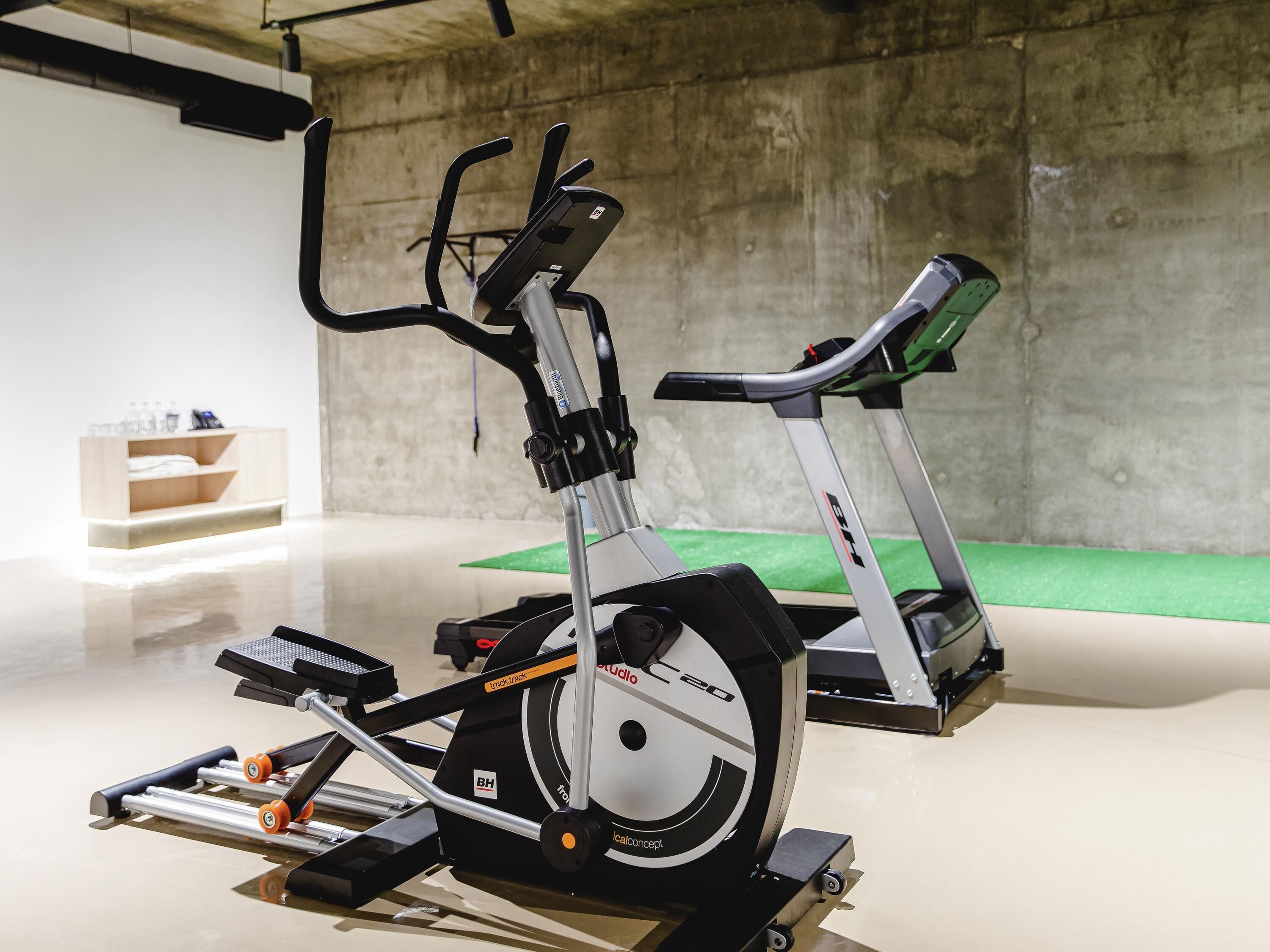 Un gimnasio interior con bicicletas estáticas y cintas de correr.
