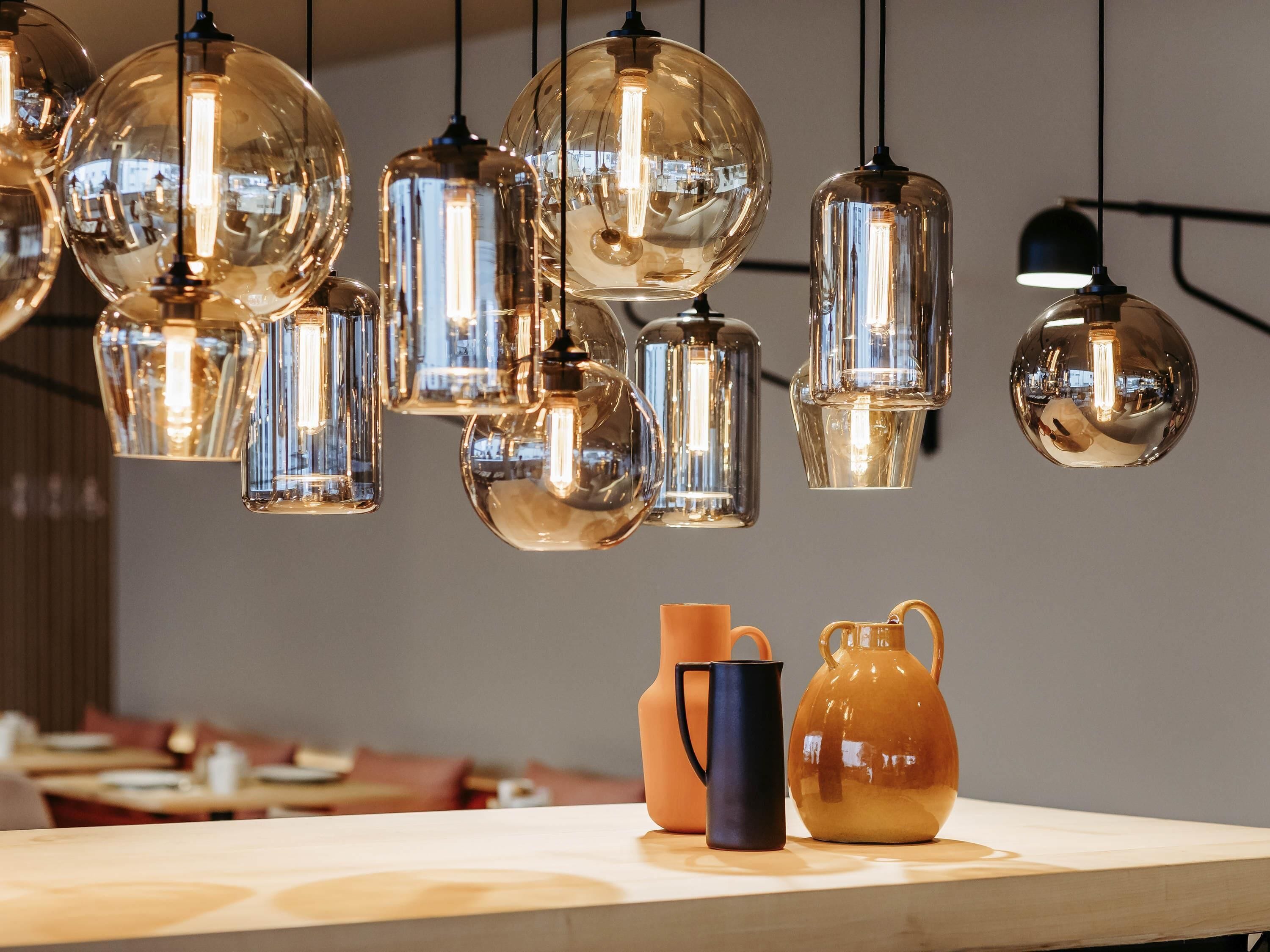 A restaurant interior with hanging spherical light fixtures and a wooden table with two pitchers.