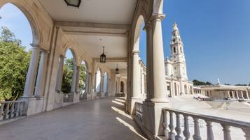 A grand architectural structure with a large open courtyard, featuring a prominent bell tower and classical columns.