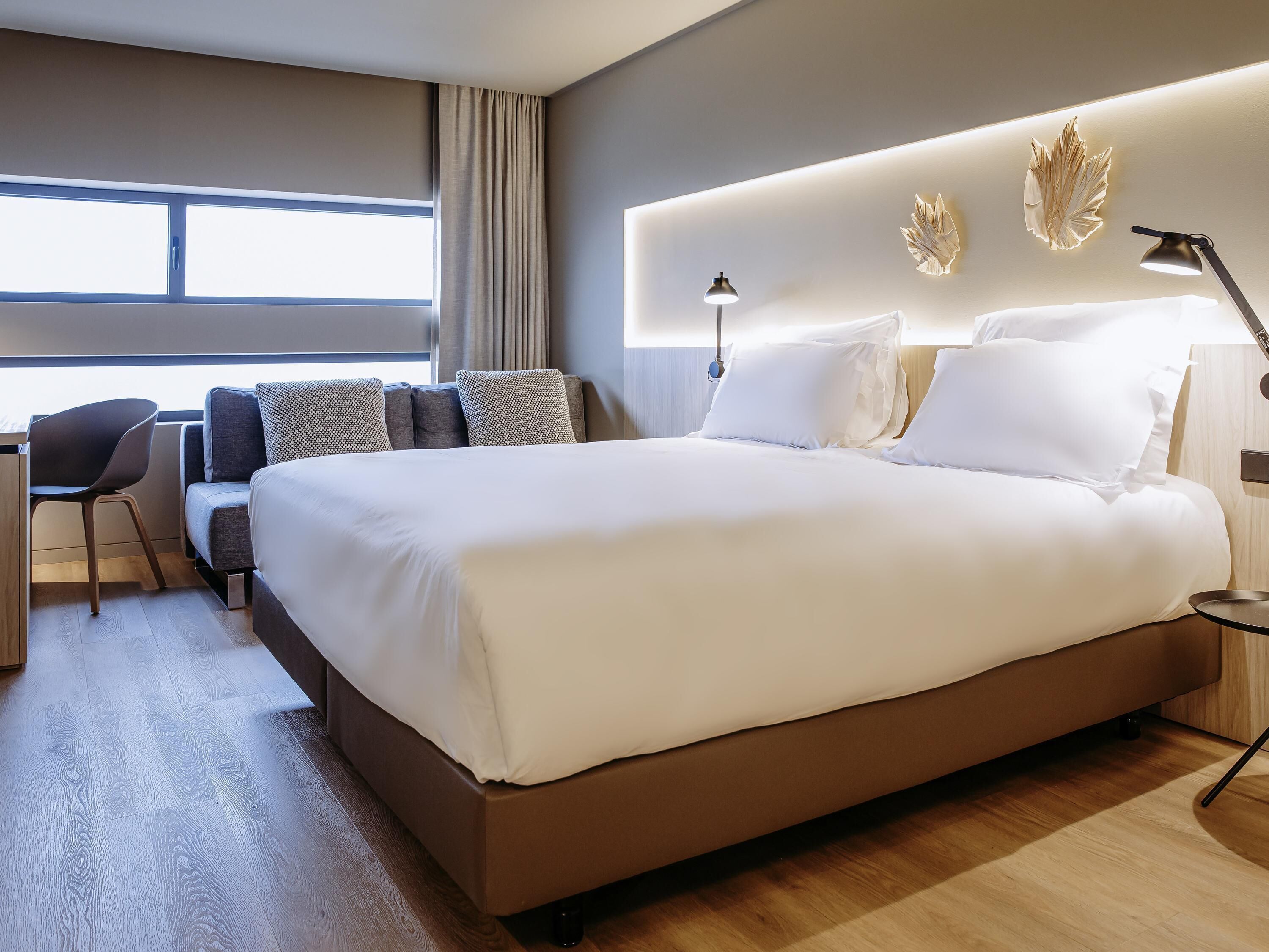 Ett modernt hotellrum med en stor säng, ett skrivbord och en stol.