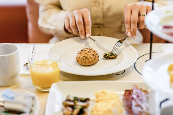 Et morgenbord med mad, et glas appelsinjuice og en kop.