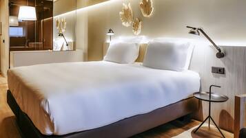 Una habitación de hotel moderna con una cama grande, lámparas de noche, una mesita y un espejo.