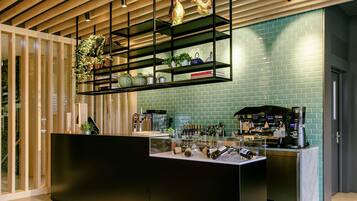 A modern bar area with a black counter, shelves with plants, and a brick wall backdrop.