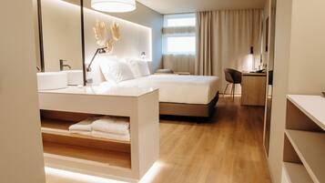 Una habitación de hotel moderna con una cama grande, una mesita de noche y un espacio de escritorio.