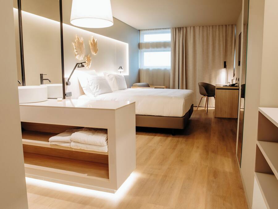 Una habitación de hotel moderna con una cama grande, una mesita de noche y un espacio de escritorio.