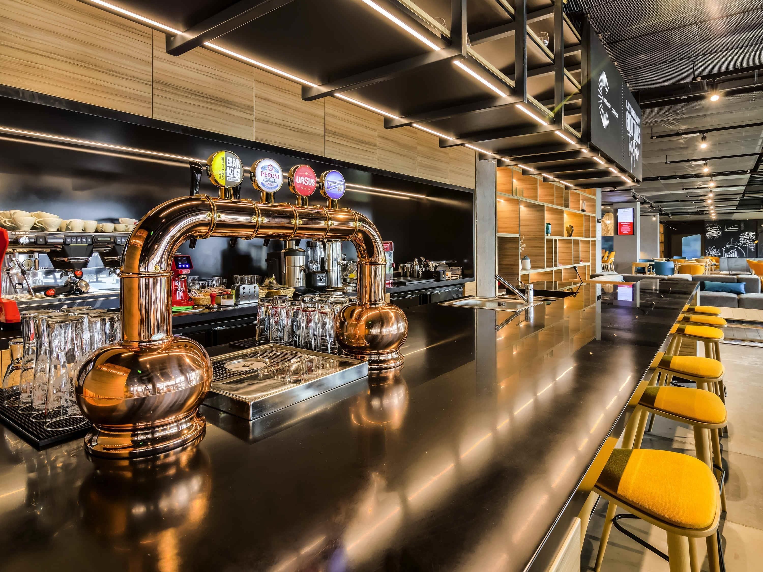 A modern bar area with a copper tap system, a bar counter, and seating.