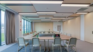 Un salón de conferencias con una larga mesa, sillas y un proyector.