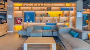 Un área de estar moderna con un sofá seccional, una mesa de centro y una estantería llena de libros y objetos decorativos.