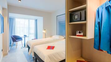 Una habitación de hotel con dos camas, un escritorio, una silla y un armario.