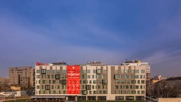A modern hotel building with a prominent red banner advertising a city center location.