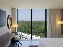 Habitación de hotel con un ventanal grande, un escritorio, una silla, una cama y un televisor.