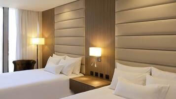 Una habitación de hotel con dos camas, un cabecero de madera, una mesita de noche y una lámpara.