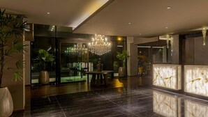 Un hall d’entrée moderne avec un sol en marbre, un lustre et des plantes en pot.