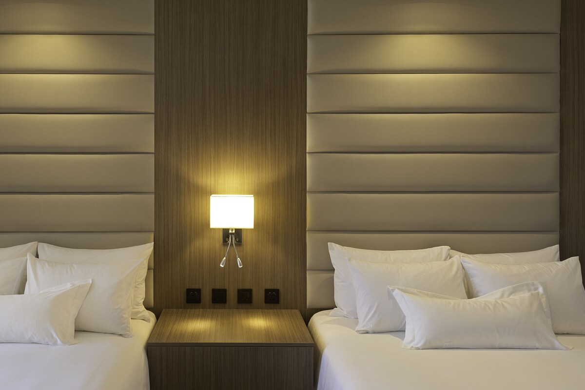 Ein Hotelzimmer mit zwei Betten, einem Nachttisch und einer Wandlampe.