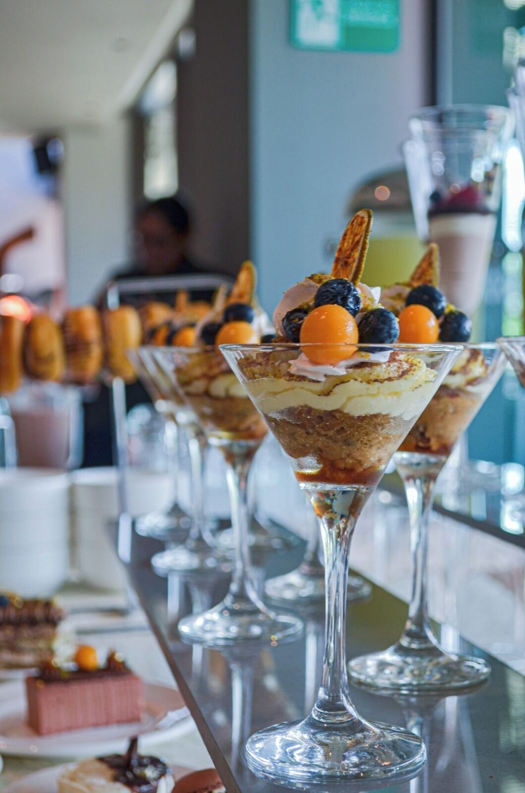 A dessert bar with various plated desserts in clear glasses.