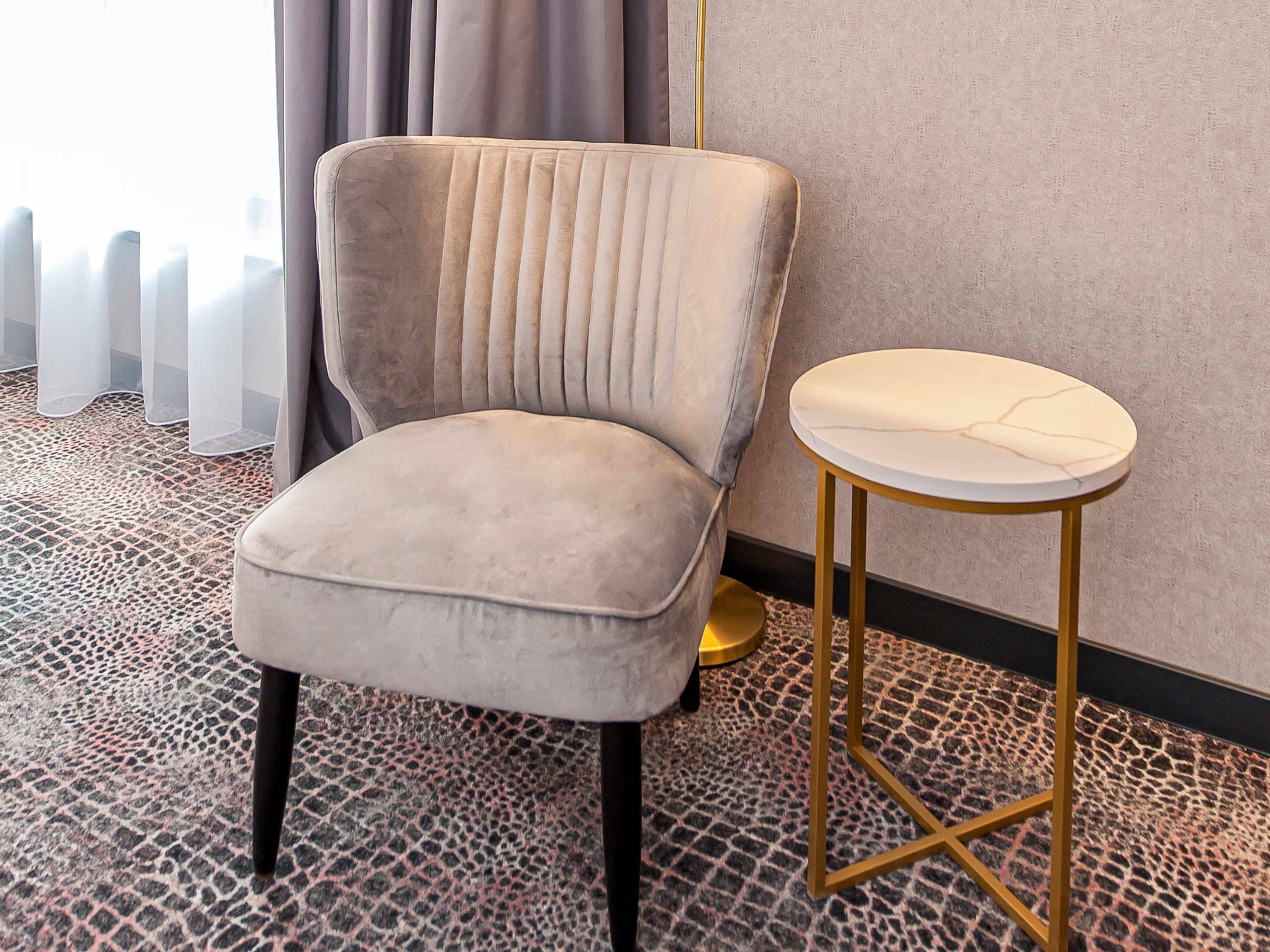 A plush armchair with a high back and a small round table with a marble top.