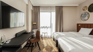 Een hotelkamer met een bed, een bureau, een stoel, een televisie en een raam met gordijnen.