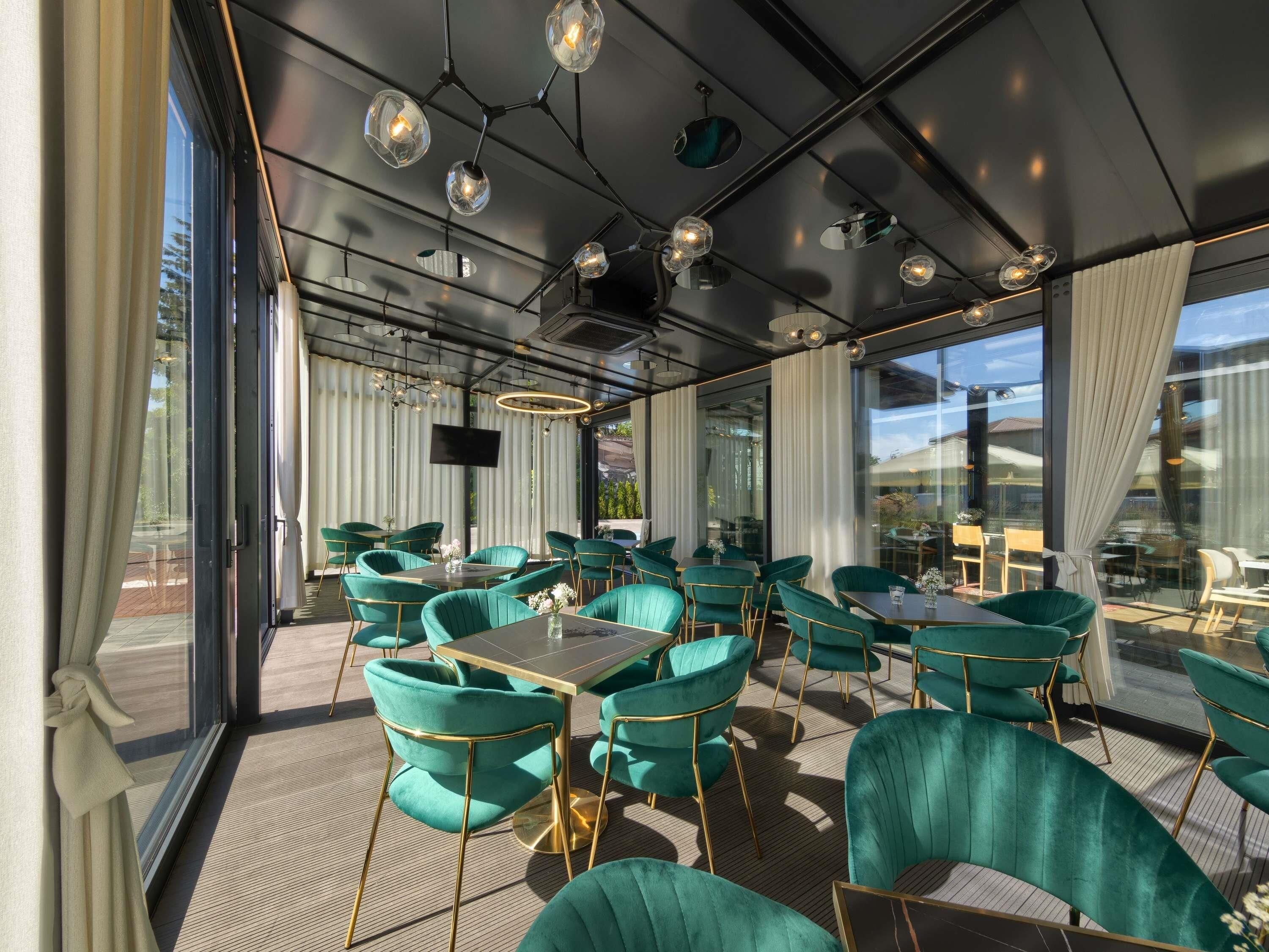 Restaurante moderno com cadeiras azul-turquesa, mesas redondas e iluminação pendente.