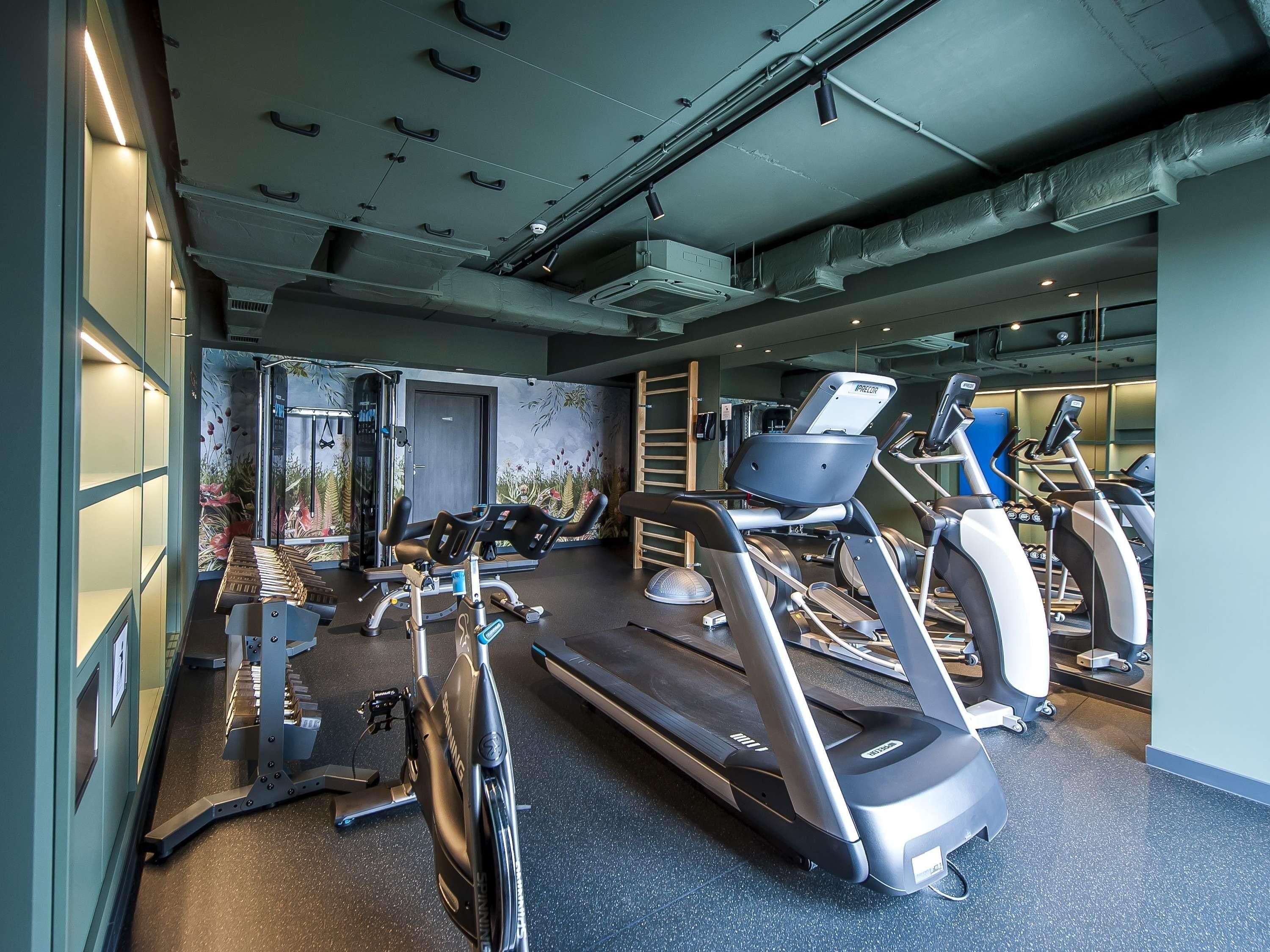 Un gimnasio con equipo de ejercicio, un espejo y una puerta que da a otra habitación.