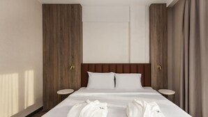 Habitación de hotel con una cama grande, paredes de paneles de madera, dos mesitas de noche y vistas al exterior.