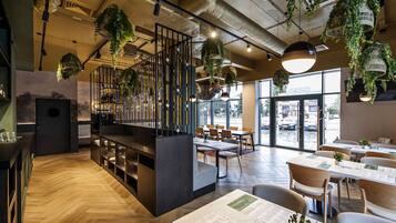 A restaurant with wooden floors, hanging plants, and a bar area.