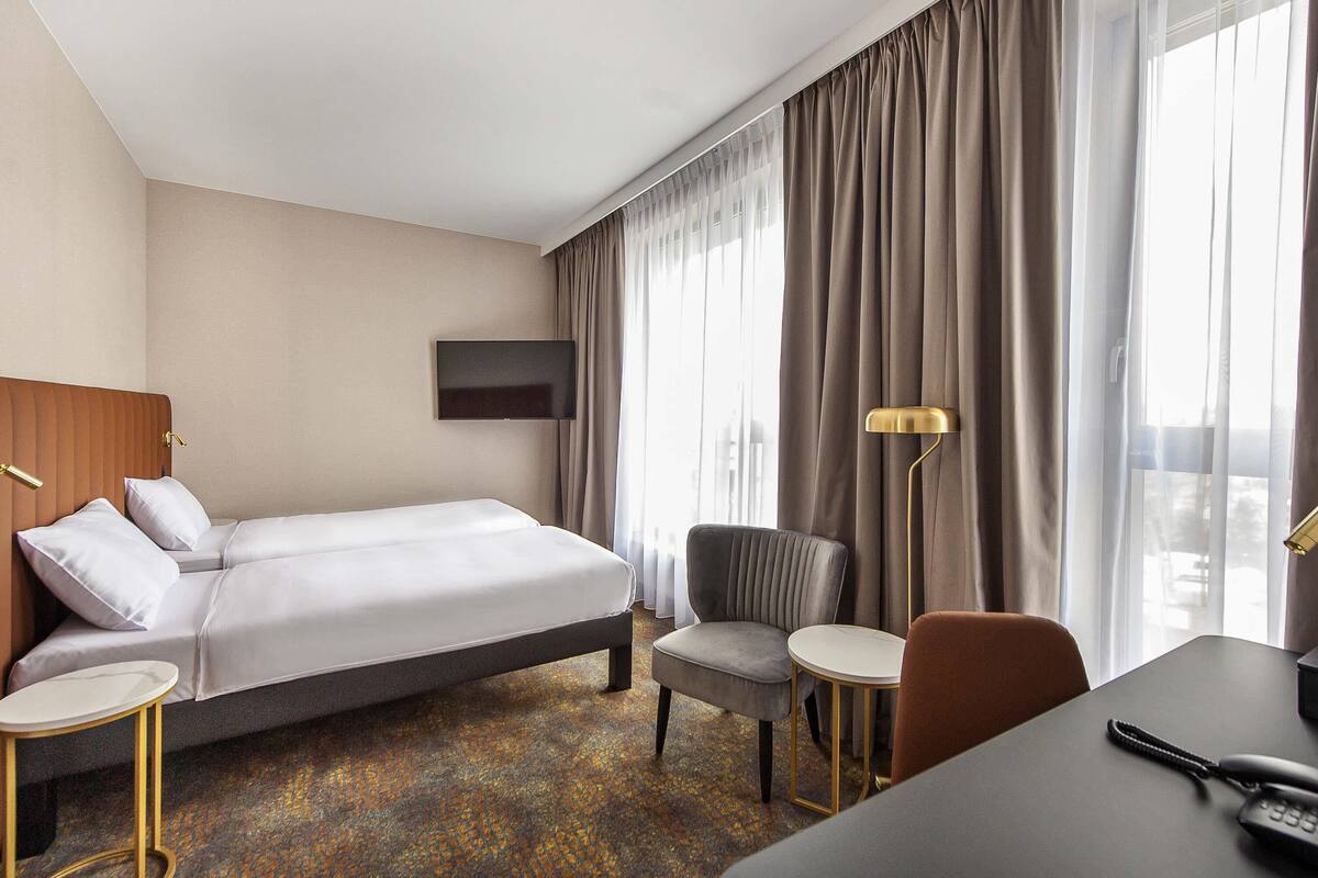 Une chambre d’hôtel avec un lit, une chaise, un bureau, une télévision et une lampe.