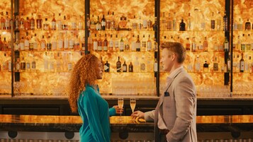 Un bar con pared de mármol y estantes llenos de botellas de licor.