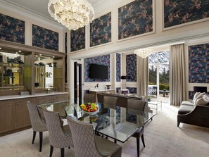 A spacious dining area with a glass table and chairs, a large chandelier, and a view of the outdoors. - Fairmont Windsor Park (Egham)