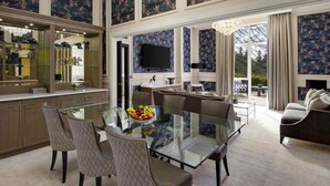 A spacious dining area with a glass table and chairs, a large chandelier, and a view of the outdoors. - Fairmont Windsor Park (Egham)