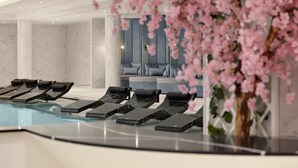 A modern spa area with a pool, lounge chairs, and a seating area with a blue wall and cushions. - Fairmont Windsor Park (Egham)