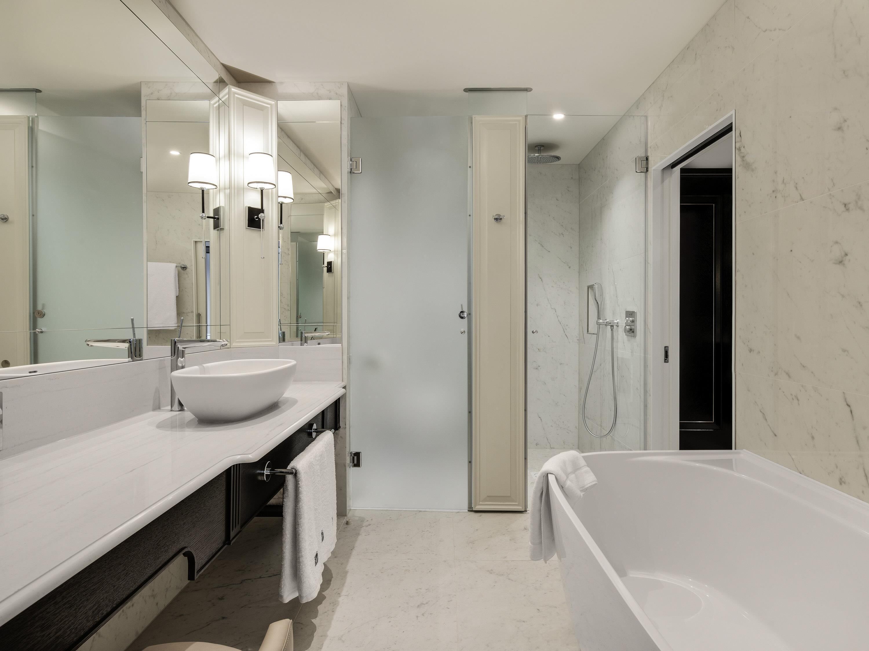 A modern bathroom with a large white bathtub, a double sink vanity, and a walk-in shower.