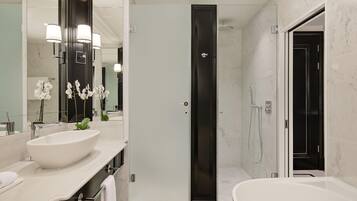 A modern bathroom with a large mirror, two sinks, a bathtub, and a shower.