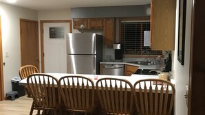 Una cocina compacta con armarios de madera, un refrigerador de acero inoxidable, un microondas y un lavamanos.