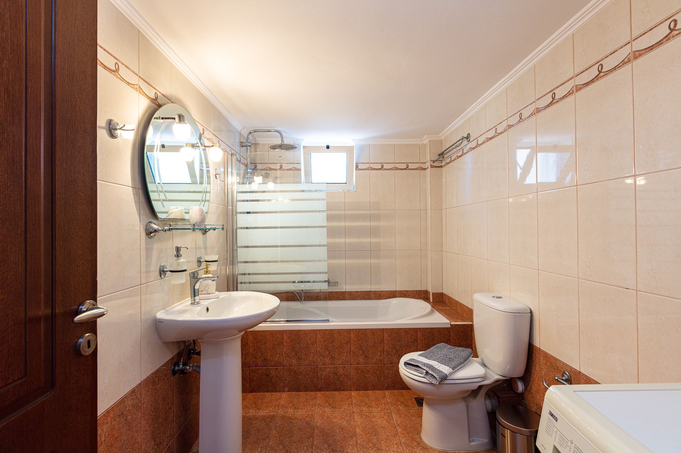 Un baño con lavabo, espejo, bañera, inodoro y ventana.
