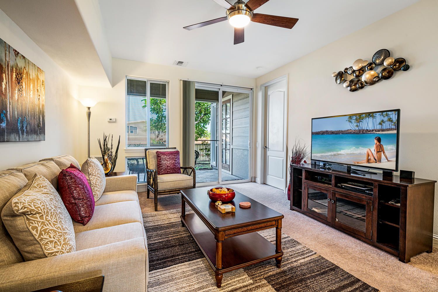 A living room with a sofa, armchairs, a coffee table, a TV, and a fireplace.