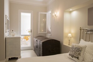 Ein Schlafzimmer mit einem Bett, einem Schminktisch, einer Kommode, einem Spiegel und einer Wandlampe.
