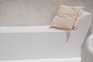 Eine weiße Badewanne mit einem beigefarbenen Kissen am Rand.