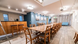 A conference room with a long wooden table and chairs, a bar area, and a blue wall with framed pictures. - Knarren Brygge (Hitra)